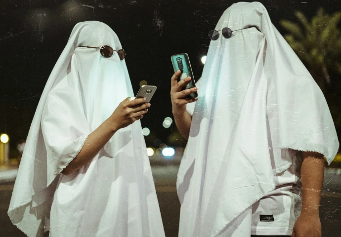 two people dressed in white are looking at a cell phone